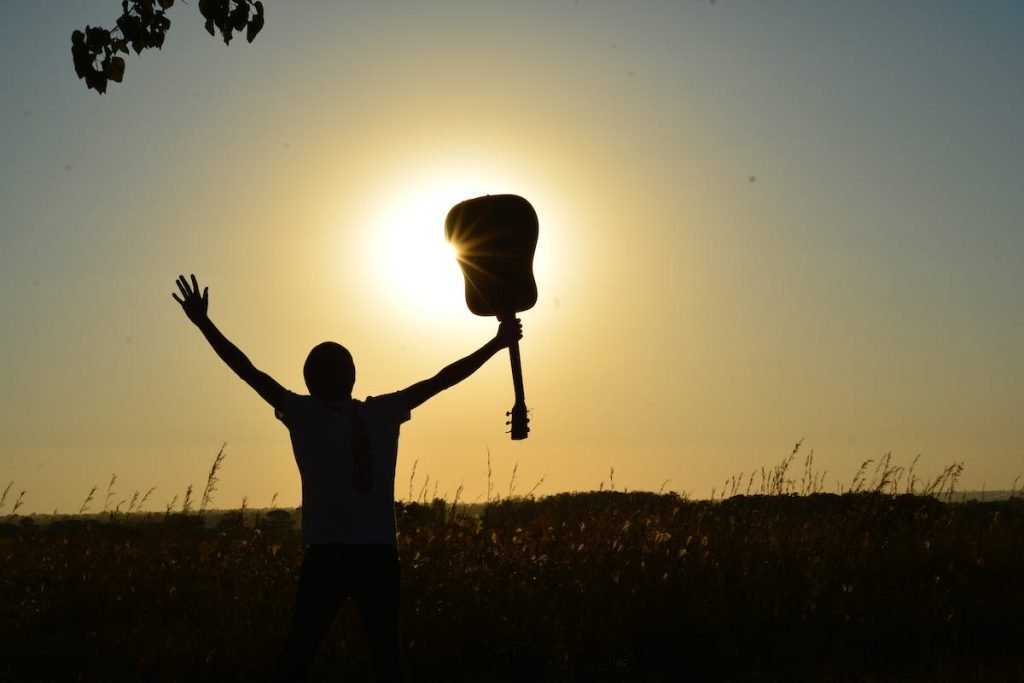 Un hombre con una guitarra acústica durante un retiro en línea al atardecer.