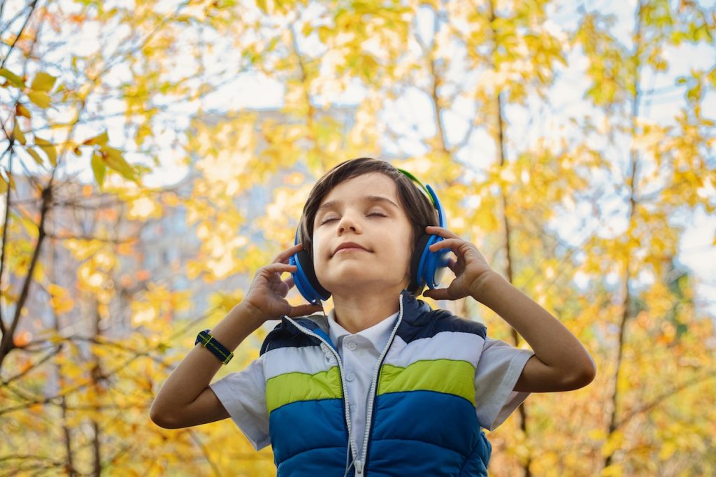 Un niño encuentra refugio mientras escucha música devocional en un parque.