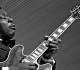 Él toca la guitarra de blues.